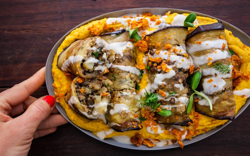 A woman's hand presenting a plant-based dish.